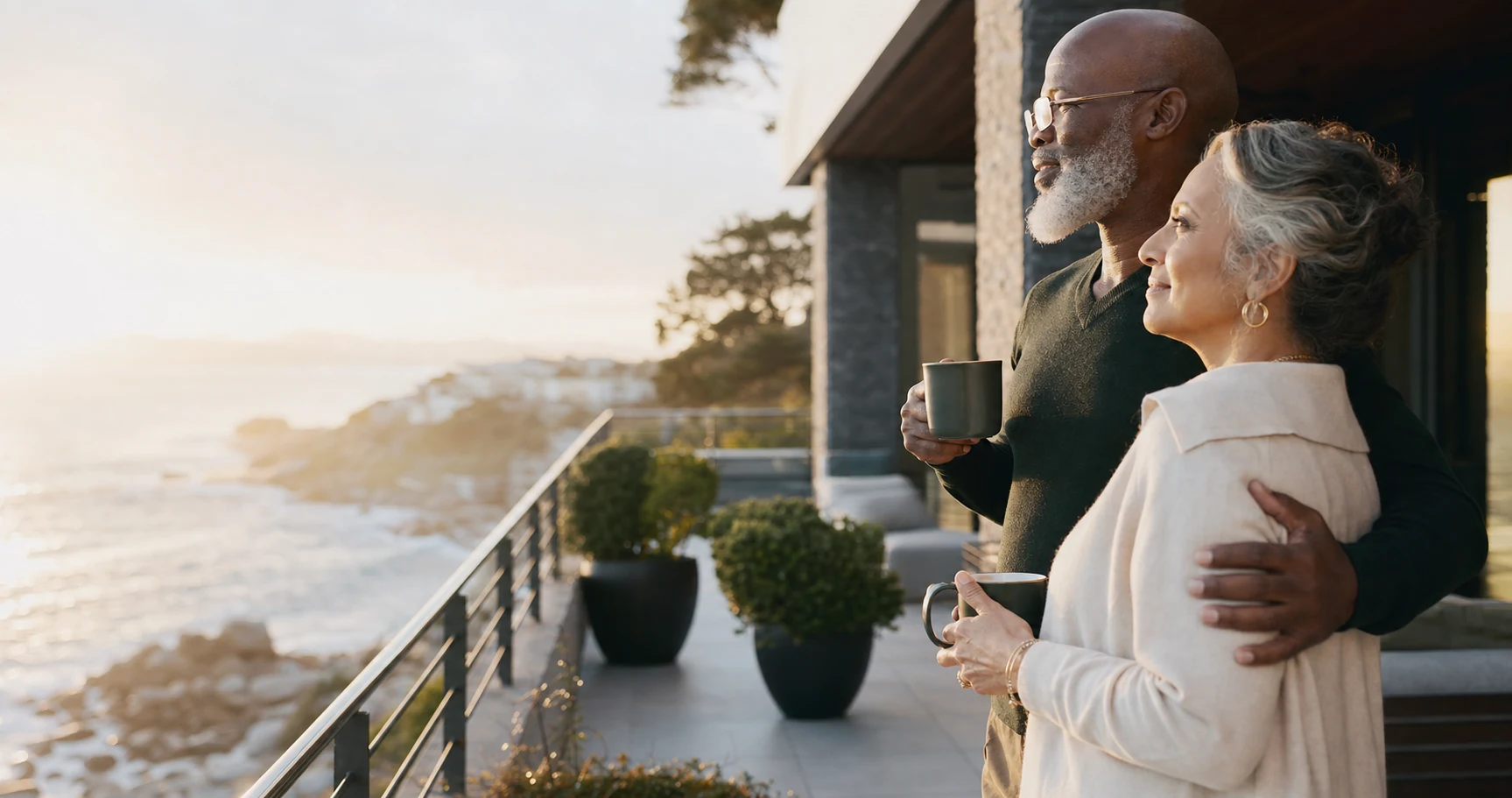 A couple enjoying a confident retirement morning on a coastal terrace
